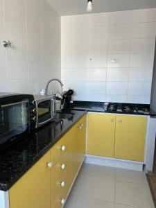 cocina con armarios amarillos y microondas en Apartamento central aconchegante.Sinta-se em casa!, en Guarapuava