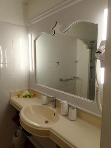 uma casa de banho com um lavatório e um espelho grande em Antigua 04 em Sainte-Luce