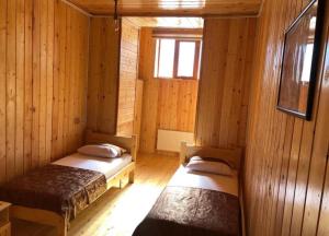 two beds in a room with wooden walls at WOOD MOTEL in Mingachevir