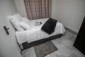 a small bed with white sheets and pillows at NTVT @ Penzance in Durban