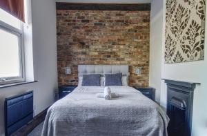 een slaapkamer met een bed met een bakstenen muur bij #1 Dunkirk by DerBnB, Modern 1 Bedroom City Centre Apartment, Free Parking, WI-FI, Netflix & Within Walking Distance of the City Centre in Derby