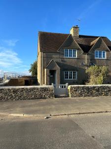 a house with a stone wall and a street at Down Ampney cottage in Down Ampney