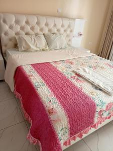 Una cama con una manta rosa y blanca. en Kigali Peace villa, en Kigali
