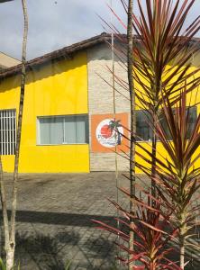 ein gelbes Gebäude mit einer Palme davor in der Unterkunft Pousada Beira-mar I in Bertioga