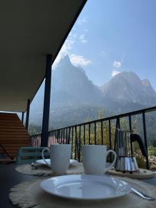 een tafel met twee koffiekopjes op een balkon met bergen bij Amontis Dolomites in Siusi