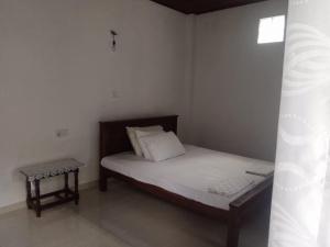 een kleine slaapkamer met een bed en een kruk bij Kandyan Guest house in Kandy