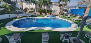 einen Pool in einem Garten mit Stühlen und einem Gebäude in der Unterkunft Hosteria Palmetto in Playas