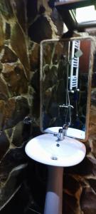 a bathroom with a white sink and a stone wall at Villa Maxi Likani in Likani