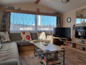 uma sala de estar com um sofá e uma televisão em hollies retreat em Lossiemouth