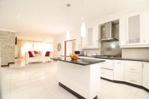 een keuken met witte kasten en een woonkamer bij Smartz Luxury Home in Centurion