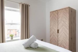 een slaapkamer met een bed, een kast en een raam bij Top Floor, City Centre, Parking in Belfast