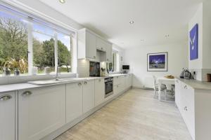 a kitchen with white cabinets and a large window at Pass the Keys Bright Cosy Cottage in Esher, West End in Esher