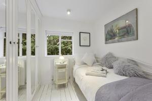 a white bedroom with two beds and a window at Pass the Keys Bright Cosy Cottage in Esher, West End in Esher