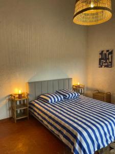 1 dormitorio con cama de rayas azul y blanco en Sole Mio, T2 avec loggia et petit aperçu mer, en Bormes-les-Mimosas