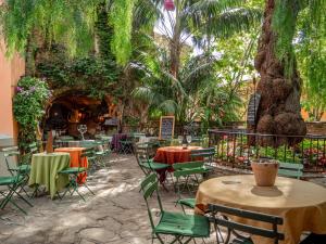 un patio al aire libre con mesas, sillas y árboles en Sole Mio, T2 avec loggia et petit aperçu mer, en Bormes-les-Mimosas