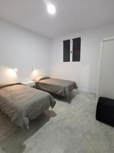 um quarto branco com 2 camas e 2 janelas em Casa Las Tías Tazacorte em Tazacorte