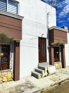 - un bâtiment blanc avec une porte rouge et des escaliers dans l'établissement apartamento a 15 mins del centro, à Tepic