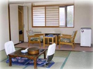 a living room with a table and chairs and a refrigerator at Hotel Masyu in Teshikaga