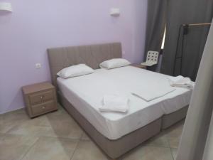 una camera da letto con letto, lenzuola e cuscini bianchi di Sappho Hotel a Skala Eresou