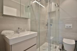 La salle de bains blanche est pourvue d'un lavabo et d'une douche. dans l'établissement Haus Schäfer, à Timmendorfer Strand
