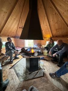 a group of people sitting around a fire in a cabin at 3ART recreation in Tromsø