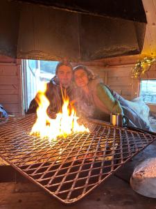 a man and a woman are cooking over a grill at 3ART recreation in Tromsø