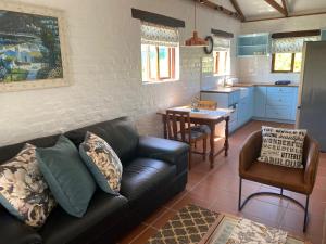 a living room with a couch and a kitchen at Hidden Stream Cottage in Bettyʼs Bay