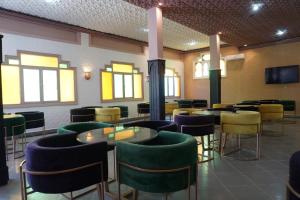 um restaurante com mesas e cadeiras verdes e amarelas em Hotel Warda em Ouarzazate