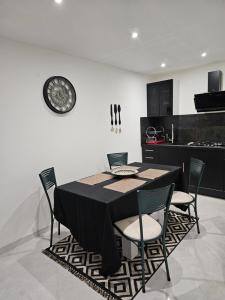 stół jadalny z krzesłami i zegarem na ścianie w obiekcie Appartement T2 bis à morbier w mieście Morbier