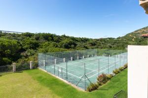 a tennis court with a net on a lawn at Stay@Tuscany - 3 Bedroom Luxury Holiday Home in Mossel Bay