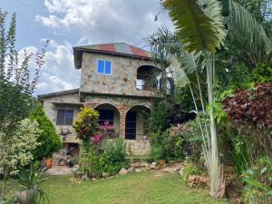 a stone house with a palm tree in front of it at Lodge au paradis fleuri 