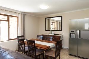 a dining room with a table and a refrigerator at Stay@Tuscany - 3 Bedroom Luxury Holiday Home in Mossel Bay
