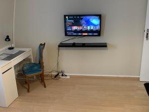 chambre cosy في Annappes: غرفة بها مكتب وتلفزيون على جدار
