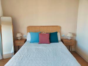 - une chambre avec un lit doté d'oreillers bleus et rouges dans l'établissement Roda Beach Apartment, à Roda de Bará