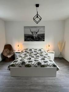 1 dormitorio con 1 cama con una pintura de toro en la pared en La petite maison, en Houyet