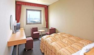 um quarto de hotel com um quarto com uma cama e uma secretária em Okura Hotel Marugame em Marugame