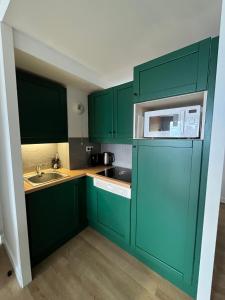 - une cuisine verte avec évier et four micro-ondes dans l'établissement Apartment Paradiski 309, à La Plagne Tarentaise