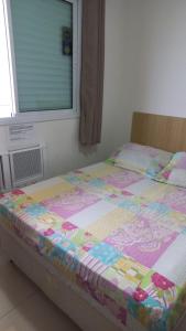 a bed with a quilt on it in a bedroom at Apto Praia Grande - Guilhermina in Praia Grande