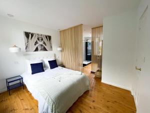 Un dormitorio con una gran cama blanca con almohadas azules. en Maison Yuki - Rose Velours - Netflix & Parking, en Le Mont-Dore
