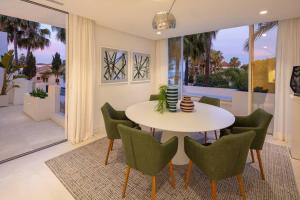 a dining room with a white table and green chairs at Stunning Duplex Apartment in Puente Romano Resort in Marbella