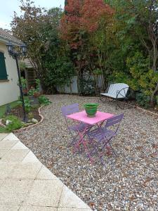 uma mesa rosa e duas cadeiras roxas num quintal em La Chataigneraie em Vernouillet