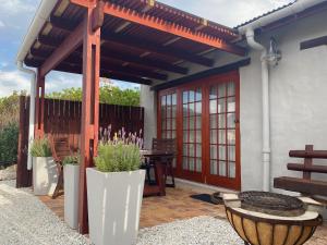 a patio with a pergola and a table and benches at Hidden Stream Cottage in Bettyʼs Bay