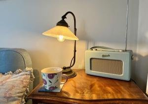 una mesa con una taza, una lámpara y un microondas en Cobblers Lodge, en Lyme Regis