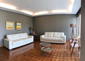 - un salon avec deux canapés blancs et une table dans l'établissement Nap Hotel, à Ponta Grossa