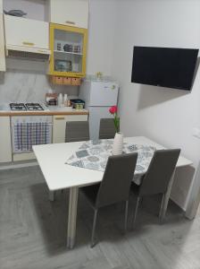 una cucina con tavolo e sedie bianchi e una cucina con TV di LA casetta 2.0 a Termini Imerese