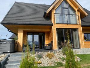 a wooden house with a black roof at Domek Panorama z Jacuzzi in Ząb