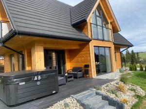 a home with a wooden deck and a house at Domek Panorama z Jacuzzi in Ząb
