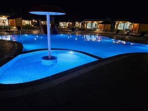 una gran piscina azul con sombrilla por la noche en SKD RESORT AND CLUB, 
