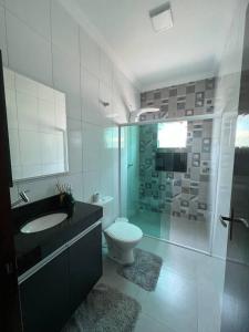 een badkamer met een toilet, een wastafel en een douche bij Casa na praia in Itanhaém