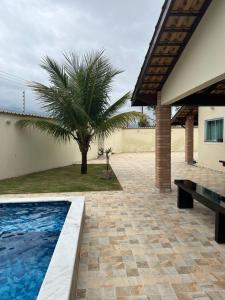a swimming pool next to a house with a palm tree at Casa na praia in Itanhaém